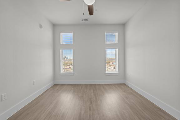 A room with a ceiling fan and two windows.