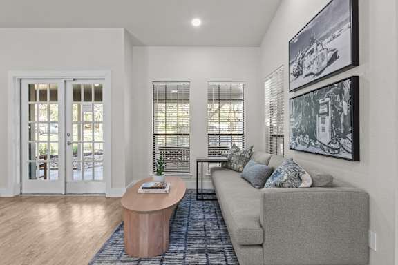 A living room with a grey couch, a wooden table, and a painting on the wall.