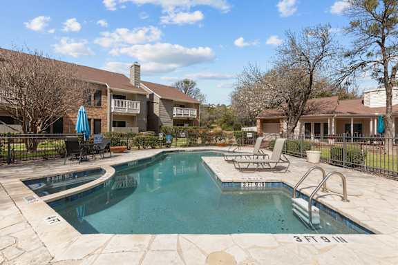 A swimming pool surrounded by a fence and chairs.