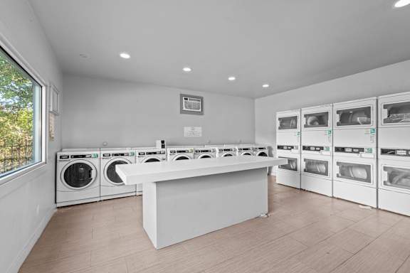 A laundry room with a white counter and multiple washing machines.