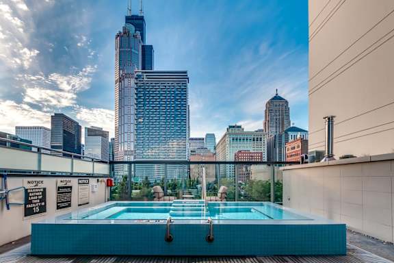 A swimming pool on a rooftop with a city skyline in the background.