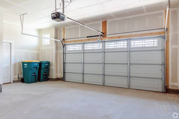 A room with a white ceiling, a white door, a white garage door, and a white wall.