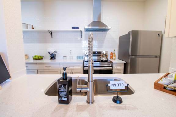 A modern kitchen with a sink and a stainless steel refrigerator.