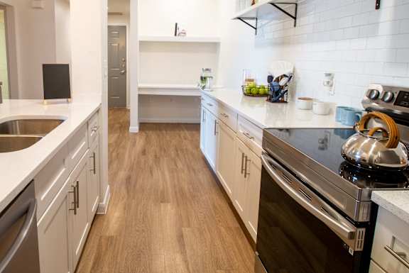 A modern kitchen with wooden floors and white cabinetry.