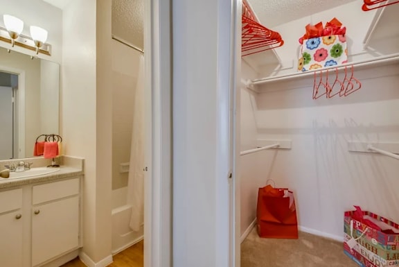 A white closet with red hangers and a red bag on the floor.