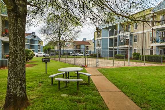 A picnic table is in the grass by a sidewalk.