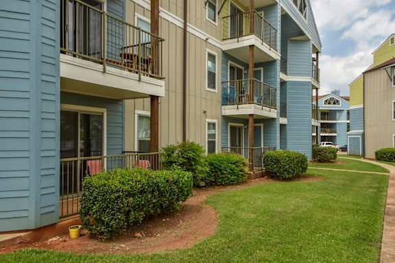 Apartment complex with blue and beige buildings and green bushes.