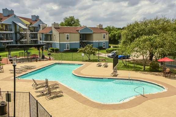 A large outdoor swimming pool surrounded by lounge chairs and umbrellas.