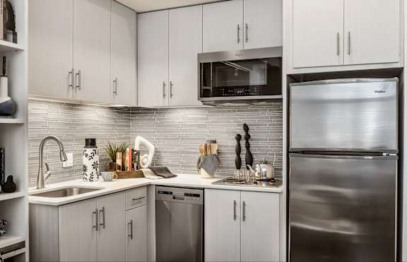 A modern kitchen with a stainless steel refrigerator and white cabinets.