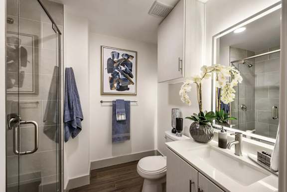 A bathroom with a toilet, sink, and a painting on the wall.