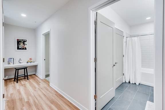 A bathroom with a white door and a white towel hanging on the shower.