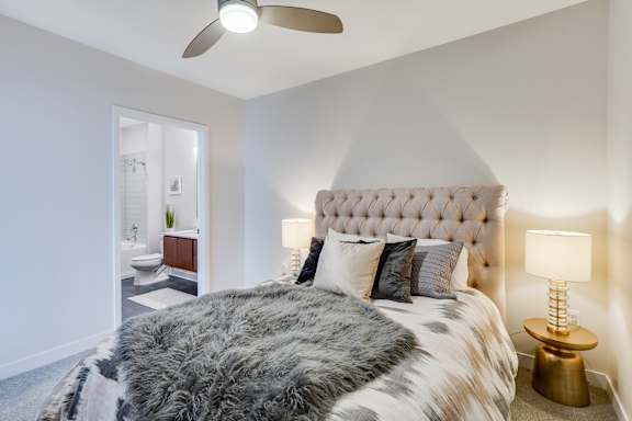 A bedroom with a large bed and a ceiling fan.