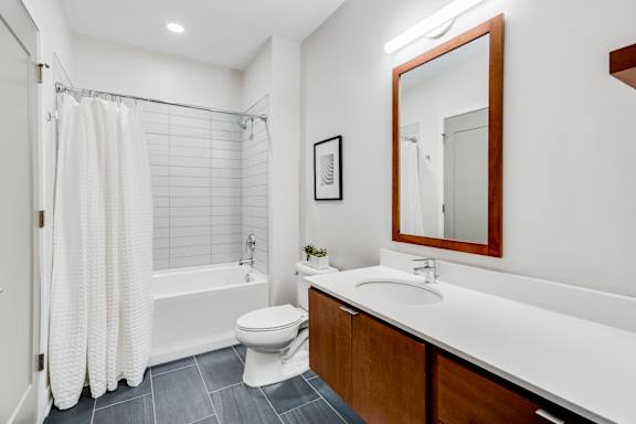 A bathroom with a white toilet, a white sink, and a white shower curtain.