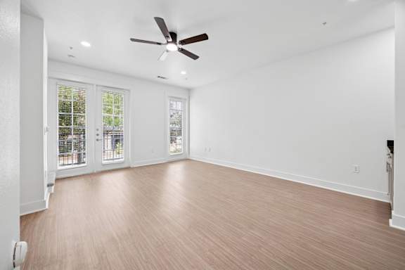 A room with a ceiling fan and wooden flooring.