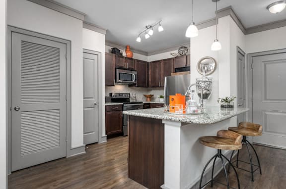 A kitchen with a white island and wooden bar stools.