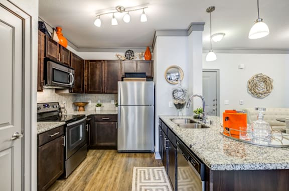 A kitchen with a refrigerator, sink, and wooden cabinets.