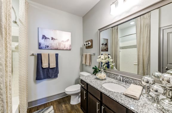 A bathroom with a toilet, sink, and a painting hanging on the wall.