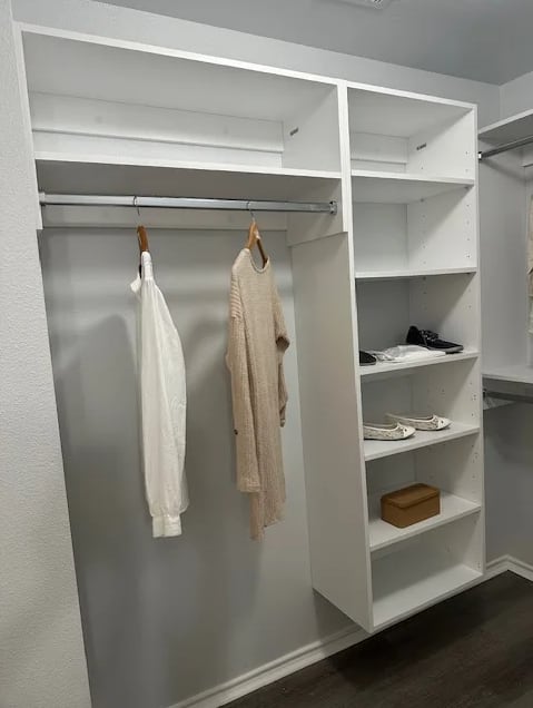 A white closet with a white shirt and tan cardigan hanging on a hanger.
