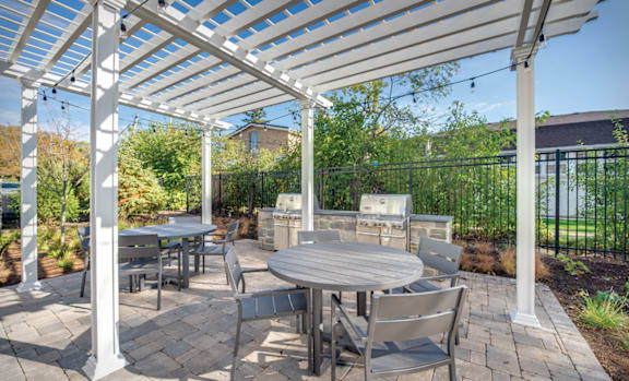 A patio with a table and chairs under a white pergola.