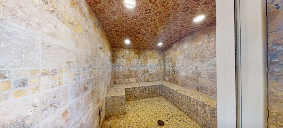 A room with a stone wall and a stone bench.