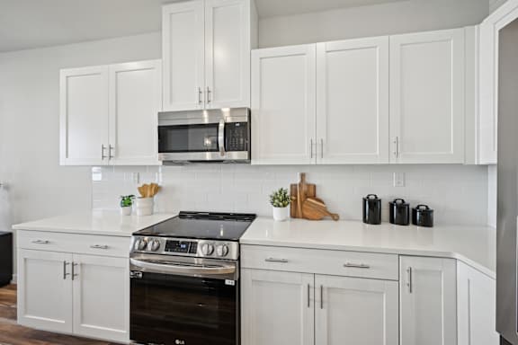 A kitchen with white cabinets and a black stove top oven.