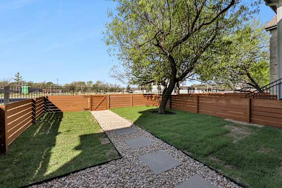 A backyard with a gravel path and a tree.