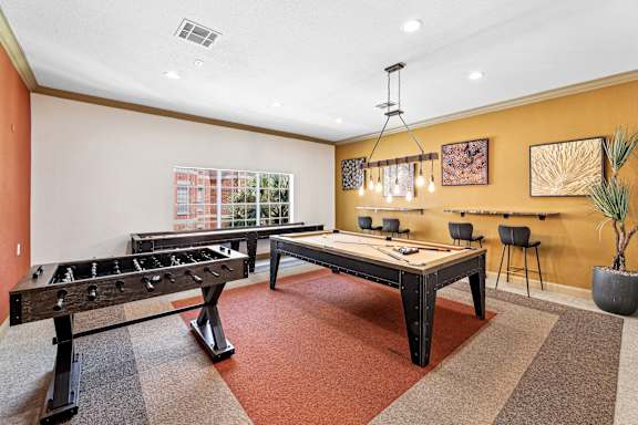 A room with a foosball table and a pool table.