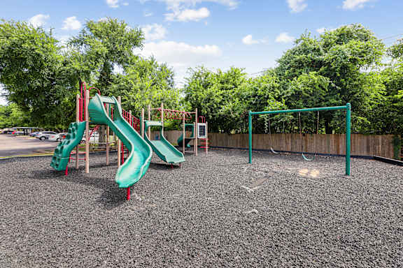 A playground with a green slide and a red slide.