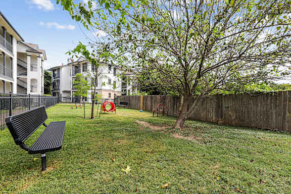 A black bench sits in a grassy yard.