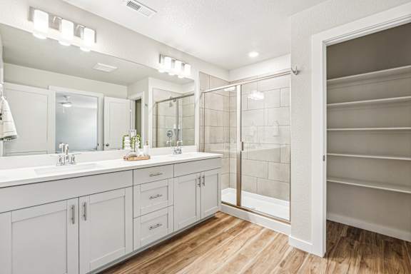 A bathroom with a walk-in shower and double sinks.
