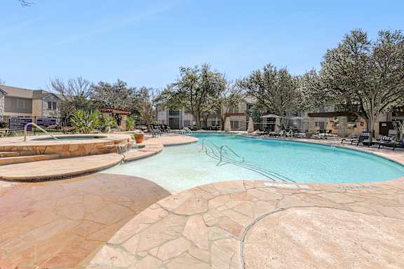 A large outdoor swimming pool surrounded by a stone patio.
