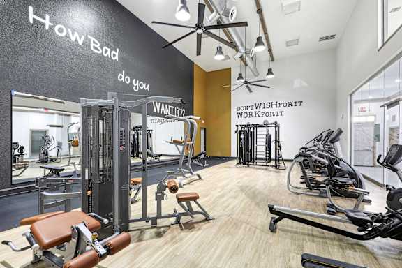 A gym with a variety of equipment including treadmills, weights, and exercise machines.