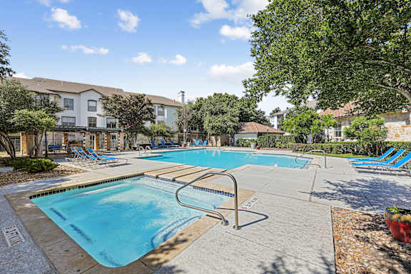 A large swimming pool surrounded by trees and chairs.