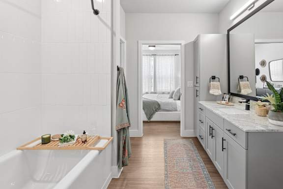 A bathroom with a white tub and a mirror.