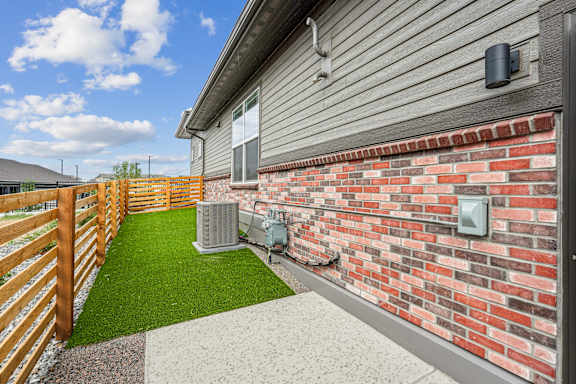 A small patio with a brick wall and a green lawn.