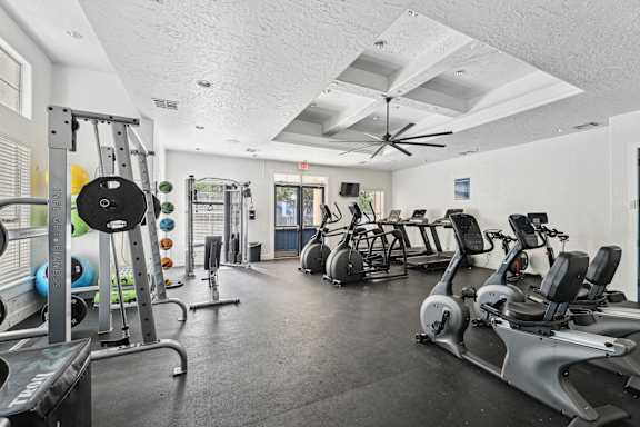 A gym with a variety of exercise equipment including treadmills, stationary bikes, and weight machines.