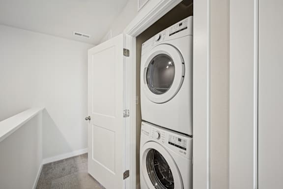 A white washing machine is in a cabinet in a room.