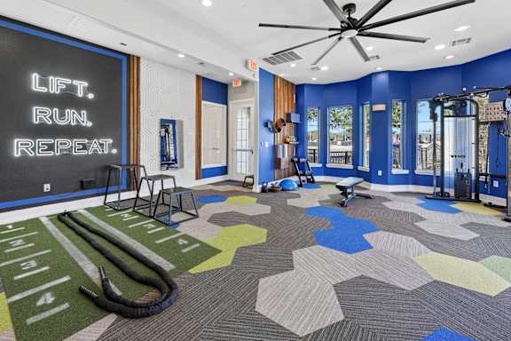 A gym with a blue wall and a sign that says "Lift. Run. Repeat."