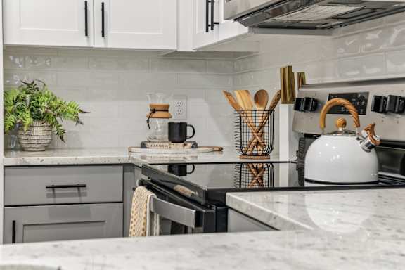 A kitchen with a white stove top oven and a white kettle on it.