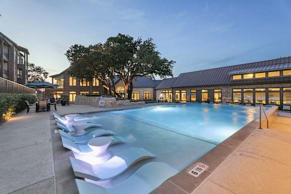 A large outdoor swimming pool with a modern design and a building in the background.