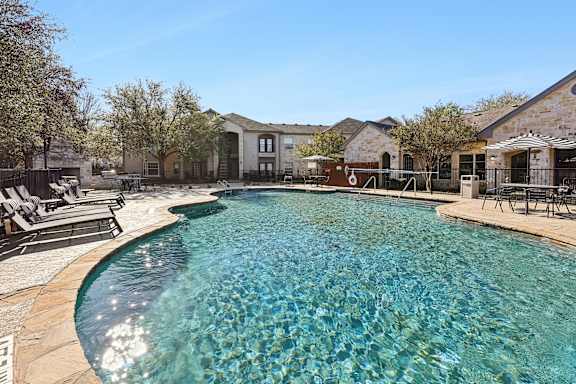 A swimming pool surrounded by chairs and buildings.