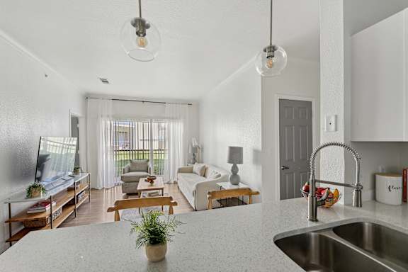 A modern kitchen with a white countertop and a stainless steel sink.