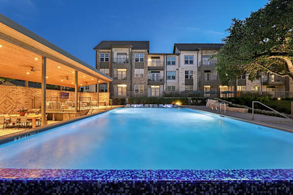 A large swimming pool in front of a building at dusk.