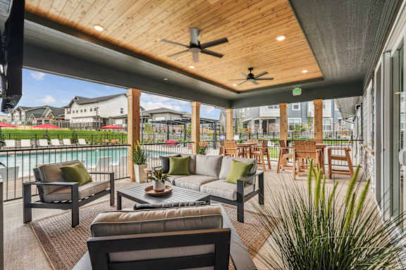 A patio with a couch, chairs, and a table with a potted plant on it.