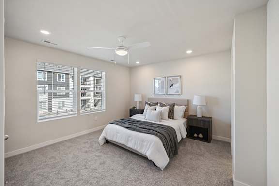 A bedroom with a large bed and a ceiling fan.