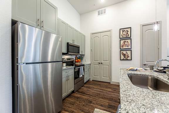 A kitchen with a stainless steel refrigerator and wooden floors.