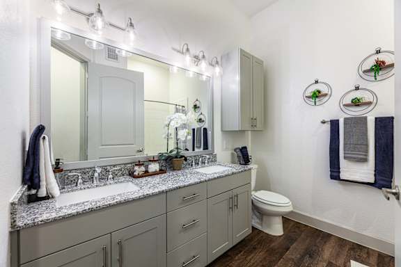 A bathroom with a white toilet, a sink with a mirror above it, and a towel hanging on the wall.
