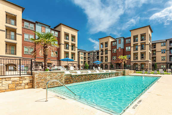 A swimming pool in front of a row of apartment buildings.