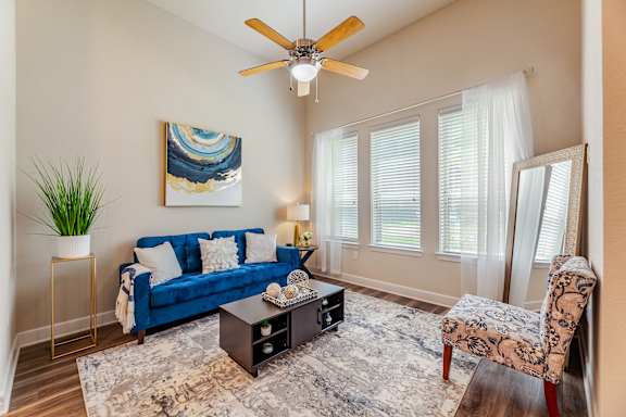 A living room with a blue couch, a coffee table, and a ceiling fan.