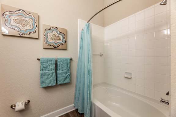 A bathroom with a white tub and a blue shower curtain.